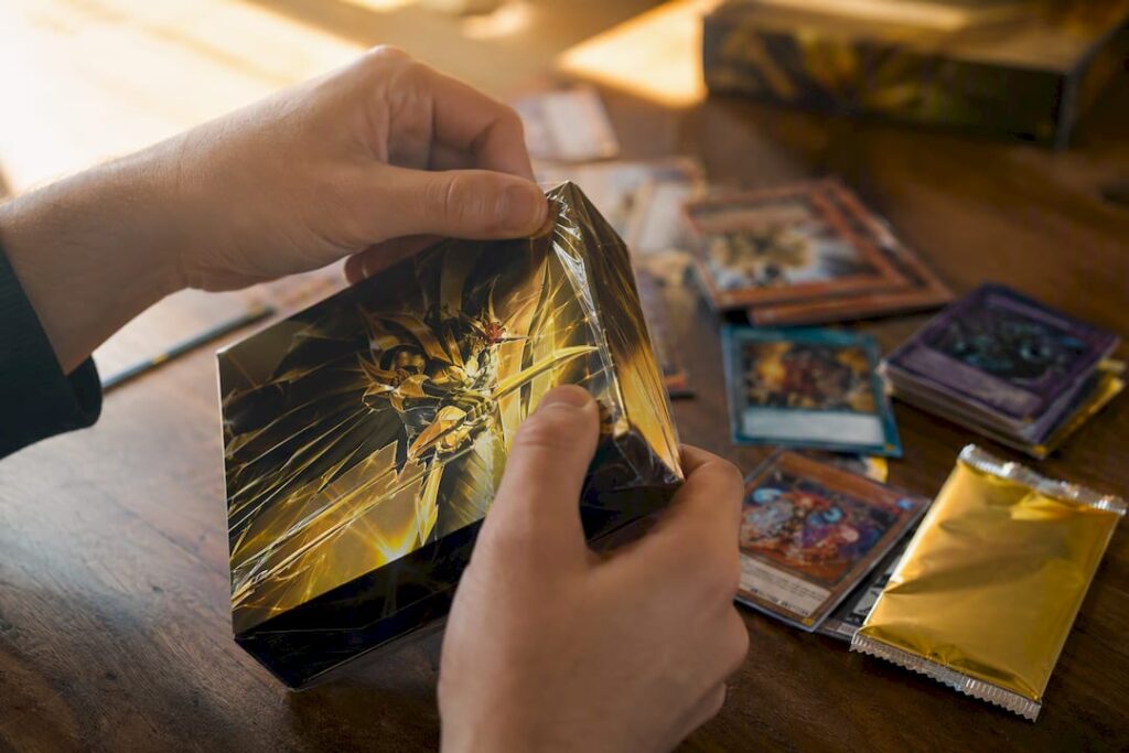 Des mains en train douvrir une toute nouvelle boîte de deck Yu Gi Oh 2026