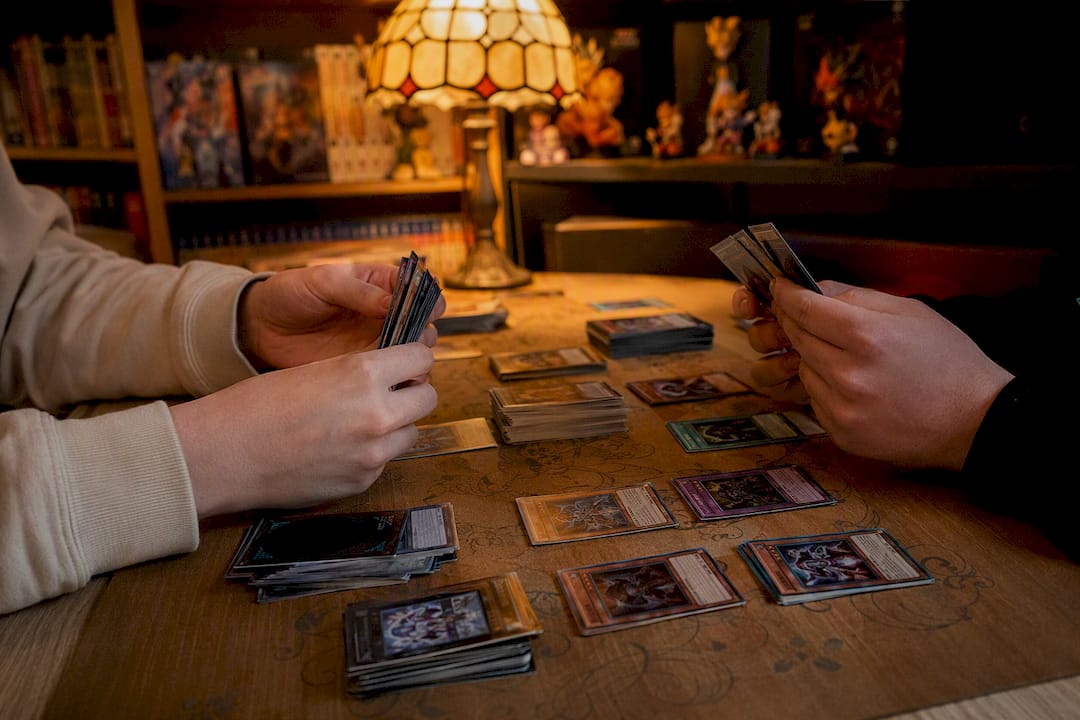 Des mains en train de disposer des cartes Yu-Gi-Oh sur une table