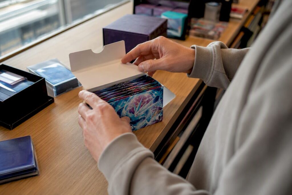 Des mains en train douvrir une boîte de boosters Pokémon