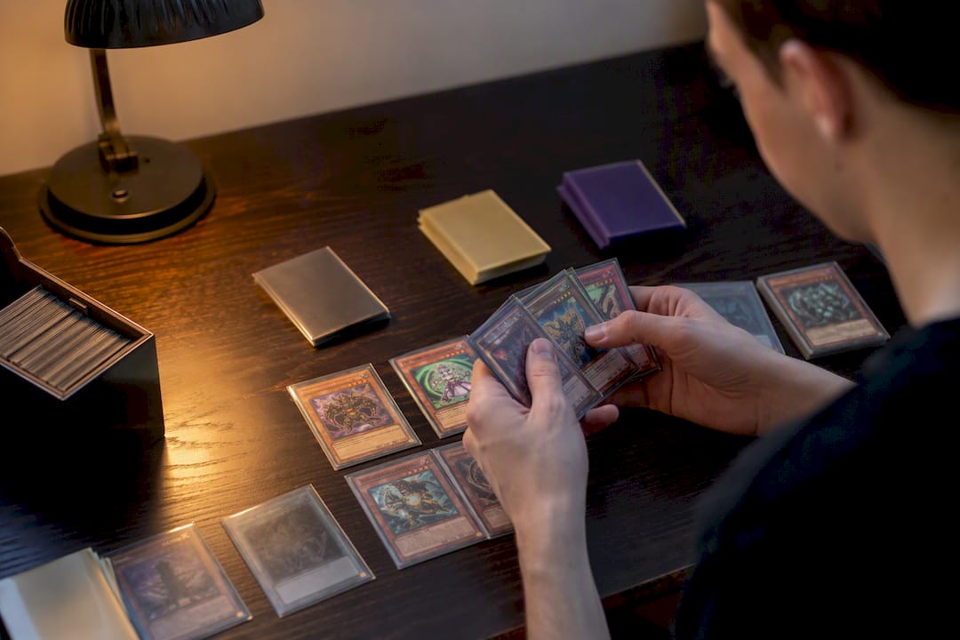 Des mains rangent des cartes Yu-Gi-Oh protégées par des pochettes